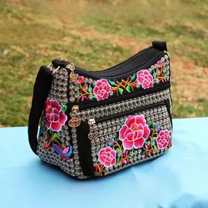 Close-up of ethnic embroidered floral pattern on a black multi-layer canvas shoulder bag