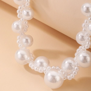 Macro view of woven faux pearl necklace detail showing smooth luster and craftsmanship