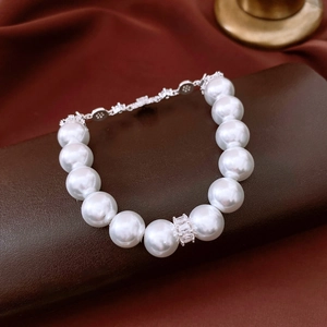 Close-up of pearl bracelet with zircon flower accents and silver metal clasp detail