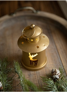 Close-up of golden vintage Christmas lantern with reindeer cutout on rustic wood base