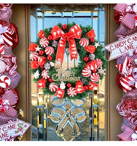 Detail eines Weihnachtskranzes mit rot gestreiften Kugeln, Schleifen und Schneemännern