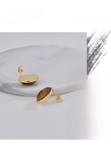 Macro view of vintage gold plated earrings with oval brown tiger eye stones