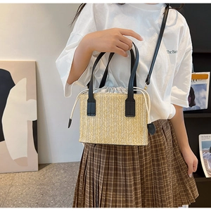 Detail of straw woven handbag with black handles and drawstring liner on model