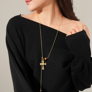 Golden cross pendant necklace with tiger eye bead on black off-shoulder top