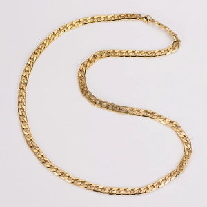Macro shot of polished gold Cuban link chain necklace with detailed engraving surface
