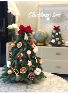 Detailed view of mini Christmas tree with red bow, pine cones and festive ornaments
