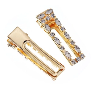 Close-up of gold hollow rectangular bridal hair clips with leaf-patterned rhinestones