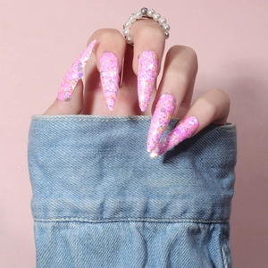Detail of long stiletto press-on nails with pink glitter and colorful sequins