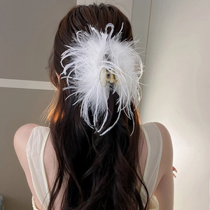 Detail shot of elegant white ostrich feather hair claw clip on brunette wavy hair