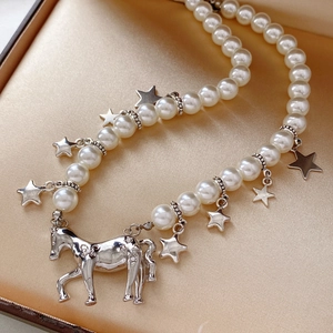 Close-up of pearl necklace with silver star charms and a horse pendant in a gift box