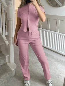 Detail of pink short sleeve button-up top and matching pants set in bright indoor lighting