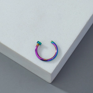 Macro view of a single iridescent rainbow metal non-piercing ring on a white marble block