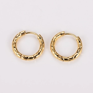 Macro detail of gold-toned hoop earrings featuring a vintage hammered texture surface