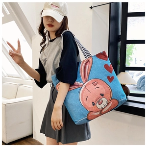 Detail of blue canvas tote bag featuring a cute pink rabbit and striped shoulder strap