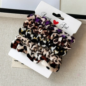 Set of 4 leopard print velvet hair scrunchies displayed on a branded card