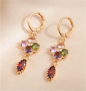 Close-up of gold drop earrings featuring colorful flower crystals and burgundy stones