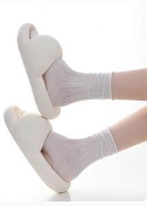 Close-up of white silk knit lace socks paired with chunky platform cloud slippers