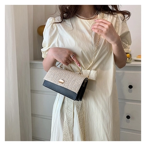 Détail du rabat en paille tressée et du sac bandoulière en cuir noir avec chaîne dorée