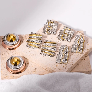 Two-tone geometric 18K gold plated stainless steel earrings on beige travertine stone