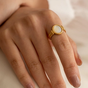 Minimalist gold ring with round white mother of pearl on female model's hand