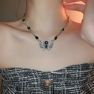Gros plan du collier papillon avec émeraudes vertes et cristaux porté par un mannequin