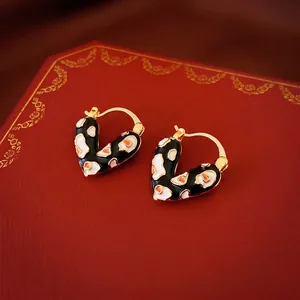 Créoles en cœur plaqué or avec émail léopard posées sur un coffret à bijoux luxe