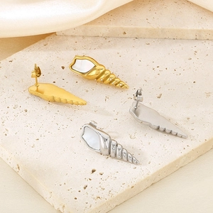 Macro detail of gold and silver conch shell earrings with pearl and crystal inlay