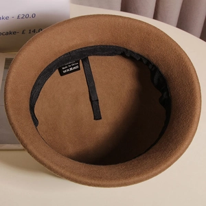 Dettaglio interno di un cappello in lana con coulisse regolabile ed etichetta di lavaggio