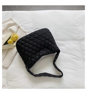 Close-up of a black quilted cloud bag with a soft texture on a white fabric background