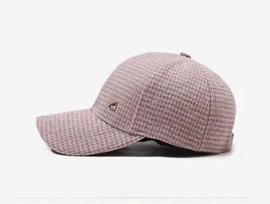 Close-up of pink and grey houndstooth wool baseball cap with side metal logo detail