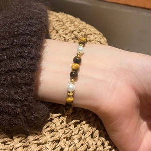Detail view of retro tiger eye and pearl beaded bracelet on a woman wrist