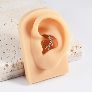 Detailed view of silver lotus petal ear cuff on silicone model against stone backdrop