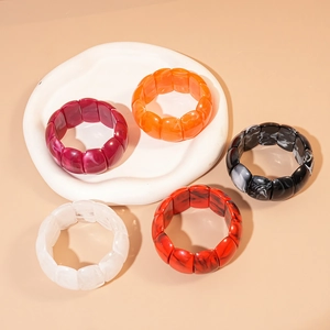 Group of colorful geometric resin cuff bracelets on an irregular white stone tray