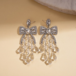 Close-up of silver bow earrings with sparkling crystal fringe and teardrop tassels