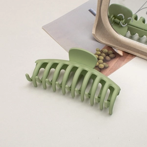 Macro view of matte avocado green large hair claw clip on a minimalist background