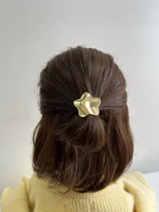 Golden geometric wave star hair tie accessory worn on a low brunette ponytail styling
