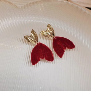 Détail de boucles d'oreilles queue de sirène en velours bordeaux et alliage doré