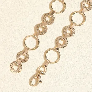 Close-up of golden metal chain belt featuring textured hammer rings and lobster clasp
