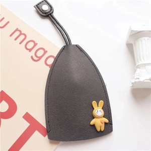 Close-up of dark grey leather key cover with snap strap and cute yellow bunny charm decoration