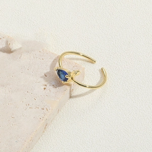 Detail of adjustable 14K gold-plated ring featuring a pear-cut dark blue gemstone inlay