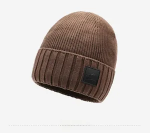Detailed close-up of dark brown knit beanie with ribbed texture and leather patch