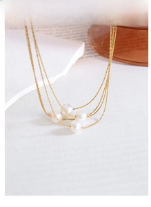 Detailed macro view of four-layer gold necklace with natural freshwater pearls