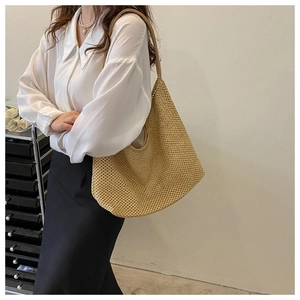 Detail of khaki woven tote bag with hollow mesh pattern and smooth leather shoulder strap