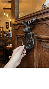 Gros plan du heurtoir de porte tête de cerf en fonte vintage sur une porte en bois