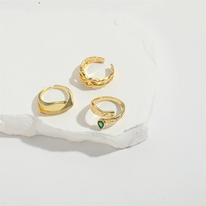 Elegant gold-plated open rings with cross-mesh textures and green teardrop gemstone details