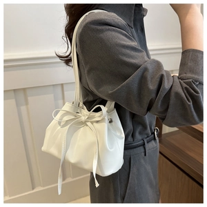 Dettaglio di una borsa a secchiello bianca con coulisse e fiocco alla moda