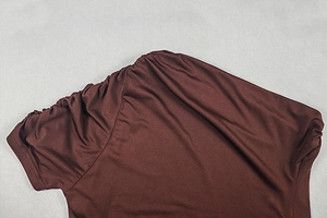 Detailed view of the pleated shoulder seam on a dark brown bodycon dress with matte texture