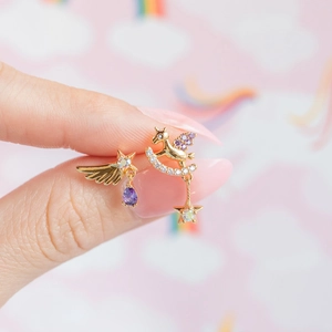 Detail of gold angel wing and pegasus stud earrings with purple crystals on cloud background