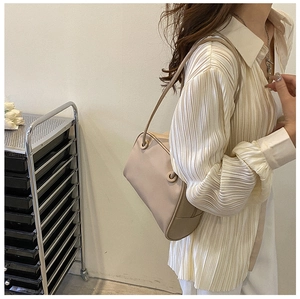 Beige faux leather shoulder bag styled with a pleated shirt in a minimalist look