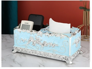 Detail of light blue tissue box with silver carving and remote control storage